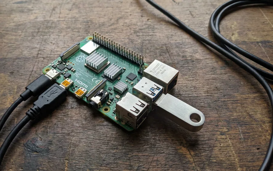 Плата Raspberry Pi 4 із підключеним USB-накопичувачем та кабелями живлення на дерев'яному столі