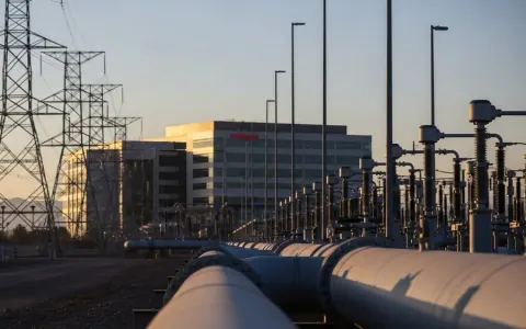 Сучасна енергетична інфраструктура Sempra Energy на заході сонця, що включає газопровід або лінії електропередач та корпоративну будівлю на фоні.